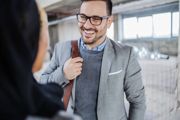 A smiling real estate professional in a suit engages in conversation at a property site.