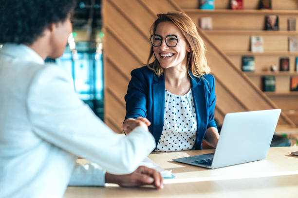 New apartment owner shaking hands with a realtor while discussing next steps in a modern office.